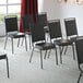 A row of Lancaster Table & Seating black banquet chairs with silver vein frames.