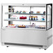 A white Turbo Air refrigerated bakery display case with cakes on it.