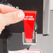A hand holding a red switch with white text that says "Lift for hot water"