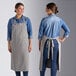 Two women wearing Acopa Ashville linen bib aprons and jeans standing in a professional kitchen.