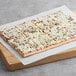A rectangular MAX whole grain breakfast pizza with meat and cheese on a wooden board.