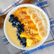 A bowl of fruit and granola with Smartfruit Mellow Mango Puree on a table.