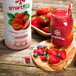 A bottle of Smartfruit Summer Strawberry puree on a table with a bowl of strawberries.