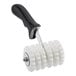 A Choice white plastic dough docker with black pointed wheels and a handle.