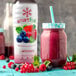 A close-up of a Smartfruit Blooming Berry Puree label on a bottle next to a glass filled with raspberry smoothie.