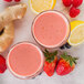 Two glasses of pink lemon smoothie with strawberries, ginger and lemon next to Smartfruit Lemon Blush Puree.