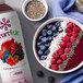 A bowl of Smartfruit Puree with berries and a drink on a table.