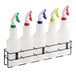 A Lavex wall-mount rack with five white spray bottles in it.