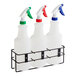 A Lavex metal rack holding three 32 oz. spray bottles. Each bottle has a white label and a different colored sprayer.