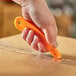 A hand holding a CrewSafe Lizard orange mini-cut utility knife to open a box.