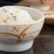 A close up of a Thunder Group white and gold melamine wave rice bowl filled with rice.