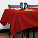 A table with a red Intedge rectangular tablecloth and a plate of food.