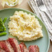 A plate of steak with mashed potatoes, asparagus and a fork on the side.