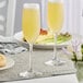 Two Libbey Vina champagne flutes filled with yellow liquid on a table.