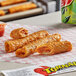 A group of fried Ruiz Foods Ranchero Beef & Cheese Taquitos on a checkered tray.