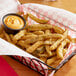 A basket of Harvest Creations Dipt'n Dusted Pickle Fries with a cup of sauce.