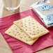 A package of unfrosted brown sugar cinnamon Pop-Tarts with a glass of milk and crackers on a napkin.