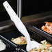 A white plastic Cambro salad bar spoon in a tray of food.