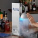 A person using an Avantco Countertop Glass Froster to chill a glass of liquid.