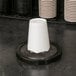 A white cup in a San Jamar in-counter cup dispenser with black gasket.