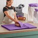 A woman wearing an apron using Lavex purple tissue paper to line a bowl.