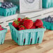 A Pactiv green molded fiber berry basket filled with strawberries and blueberries on a table.
