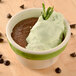 A CAC stoneware bouillon bowl filled with chocolate pudding topped with whipped cream and mint leaves.