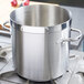 A large silver stainless steel Vollrath stock pot on a stove.