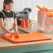 A woman cutting Lavex orange tissue paper on a counter.
