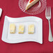 A Fineline white plastic dessert plate with a slice of yellow cake and a fork.