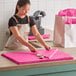 A woman cutting a pink Lavex tissue paper sheet on a table.