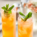 Two glasses of pink guava puree with mint leaves on top.