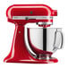 A red KitchenAid Artisan mixer with a stainless steel bowl.