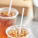 A close-up of a couple of plastic cups with Choice jumbo clear wrapped straws in them.