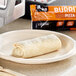 An Alpha Foods Plant-Based Pizza Burrito on a plate next to a microwave.