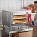 A man putting a pizza in an Avantco double deck countertop oven.