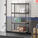 A Lavex black metal boltless shelving unit holding containers on particleboard shelves.