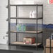 A Lavex black metal boltless shelving unit with shelves holding bottles and boxes.