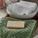 A FarmHouse Fresh Botanical Blend body bar soap in a white box on a towel next to a bowl.