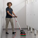 A woman using the Hoover Orbital CH80100 multi-purpose floor cleaner to scrub a floor.