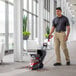 A man using a Hoover PowerScrub carpet spotter to clean a carpet.