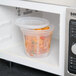 A Pactiv translucent plastic deli container with food inside of a microwave.