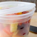 A Pactiv translucent plastic deli container filled with fruit and vegetables on a counter.
