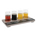 A Cal-Mil wooden flight tray with different colored beers on it, with a black write-on surface at a brewery.