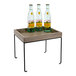 A Cal-Mil gray-washed pine wood display riser with a metal base holding three clear plastic bottles of water on a table.