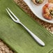 An Acopa stainless steel escargot fork on a green napkin.