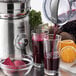 A Breville commercial juicer pouring red juice into a glass.