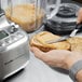 A person uses a Breville commercial blender to cut a piece of bread on a counter.