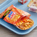 A tray with a bag of Chex Mix Cheddar Snack Mix and a box of cheese crackers on a table.