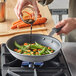 A person pouring a sauce into a Vollrath Wear-Ever non-stick fry pan on a stove.